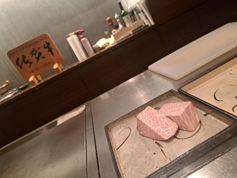 写真：奥の棚に佐賀牛ブランドロゴの木製プレートが展示されている。手前のカウンターに熟成が進んだ佐賀牛ロース肉のかたまりがある様子