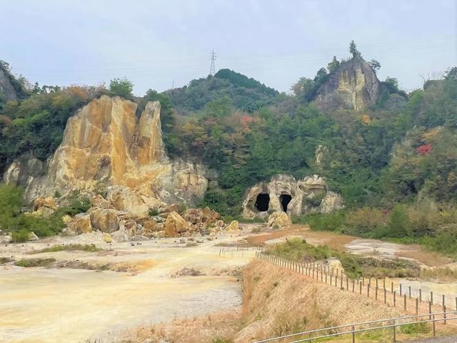 写真：岩肌がむき出しになった山。採石の跡の大きな穴が2つ空いている