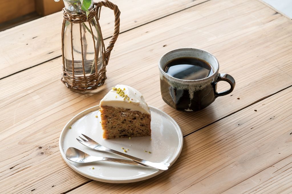 写真：木製テーブルにコーヒーカップと素朴なケーキが並んでいる様子