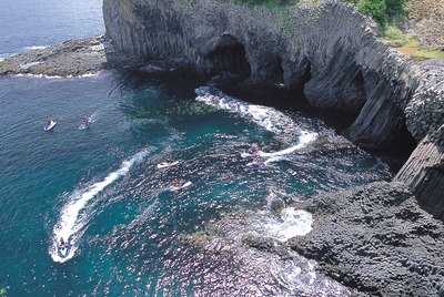 写真：洞窟のある崖と海と白い船