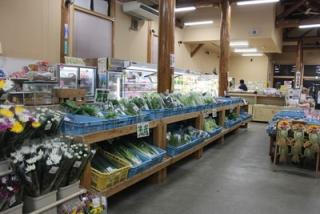 写真：菊などの生花、ネギなどの野菜が並ぶ店内
