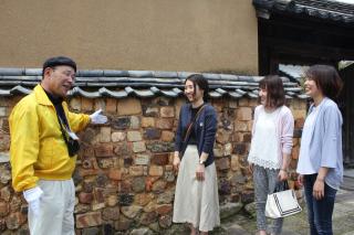 写真：黄色い上着のガイドが女性に陶器でできたトンバイ塀の説明をしている