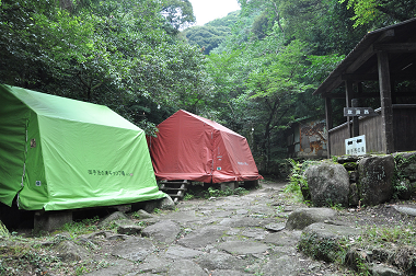 写真：山に緑のテントと赤のテントが張られている