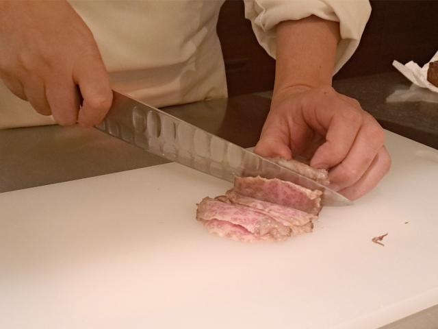 写真：焼いた肉を包丁でスライスする手元