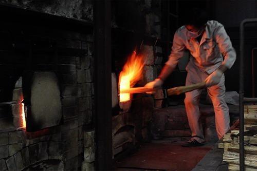 写真：熱い源右衛門窯の中に薪をくべる男性の写真