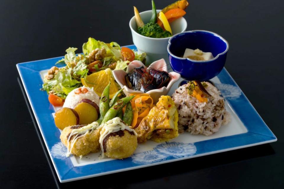 写真：豆腐カツ、グリーンサラダ、煮物の小鉢、雑穀米ご飯などがワンプレートに盛られた料理