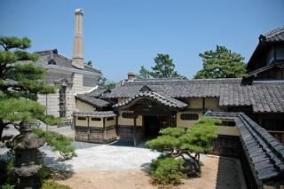 写真：平屋で瓦葺の大きな日本家屋、奥に煙突が見えている。