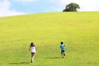 写真：原っぱを走る二人の子供