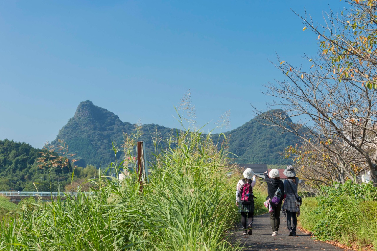 写真：御船山を背景に小道を歩く3人の女性