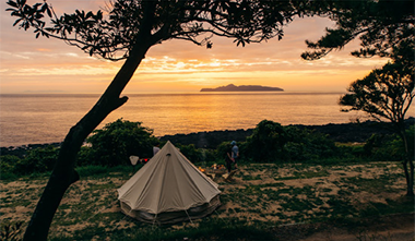 写真：夕日が沈む海の前のテント
