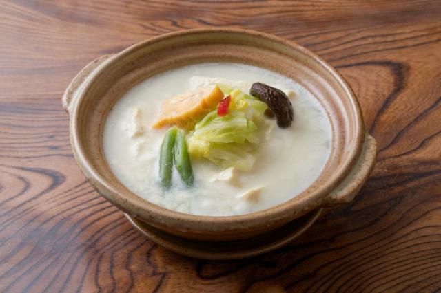 茶色の鍋に野菜や卵焼きが乗った温泉湯豆腐の画像