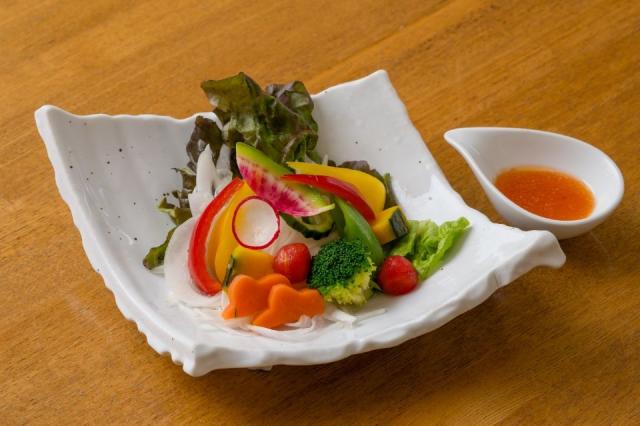 トマト、レタス、パプリカなどが使われたいと鮮やかな野菜サラダとドレッシングの画像