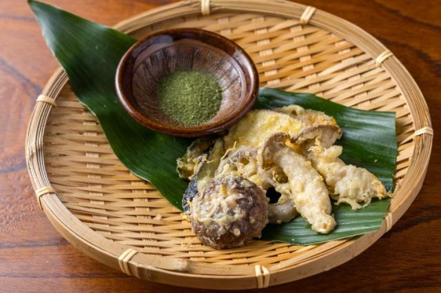 ざるの上に野菜とキノコの天ぷらと抹茶塩がおかれた料理画像