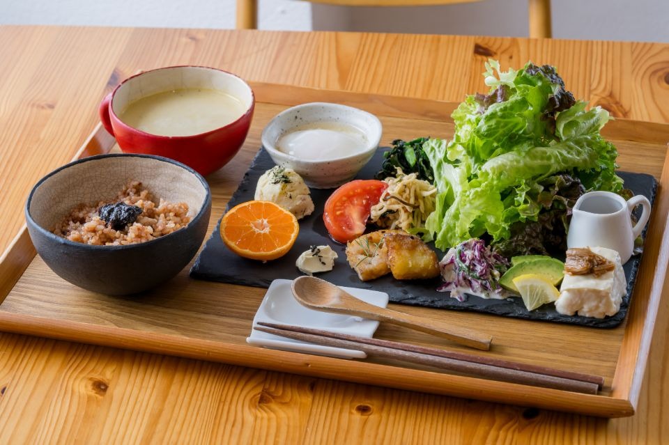 木製のお盆に左から玄米ご飯、スープ、四角の皿に複数の野菜料理が盛られたものが並べられた画像