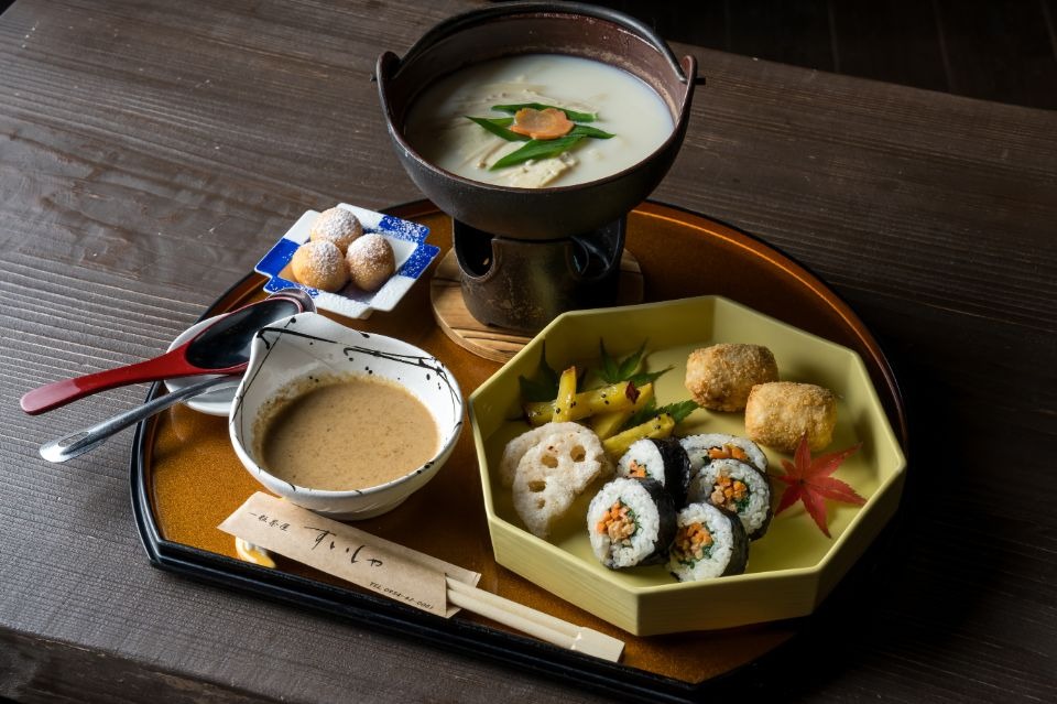手前の黄色の皿に海苔巻き、おからコロッケ、レンコンの天ぷらが盛られ、奥に温泉湯豆腐、だし、豆腐ドーナツが並べられた画像