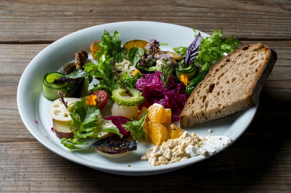 白く丸い皿にパンと多様な野菜が盛られた料理画像