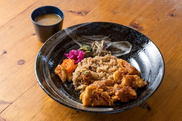 丸く黒い皿に大豆ミートのヤンニョムチキンとご飯が盛られ、スープが添えられた画像