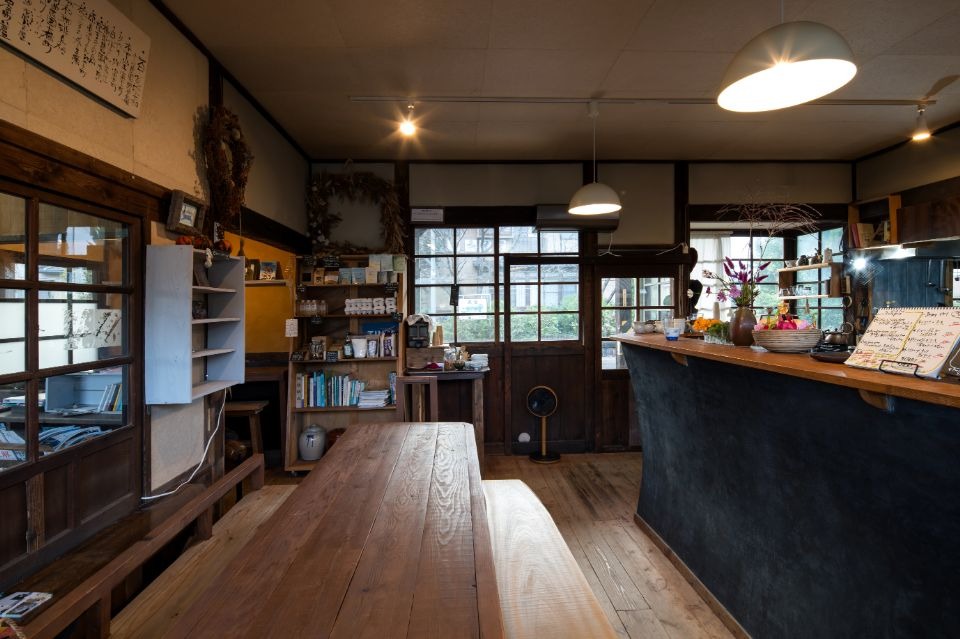 木製の床の上に、中央に木製のテーブルが置かれ、右にカウンターがある店内画像