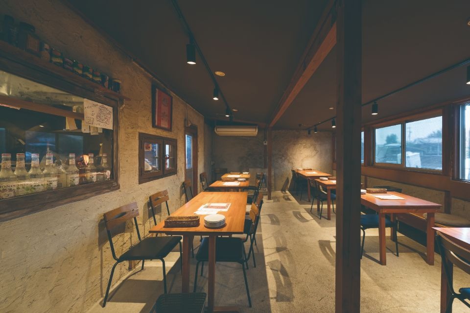 ベージュの床と壁に木製のテーブル、椅子が並んだ店舗内観画像