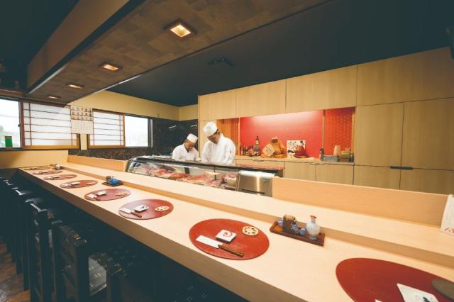 寿司屋のカウンターがあり、その奥に職人が二人寿司を握っている画像
