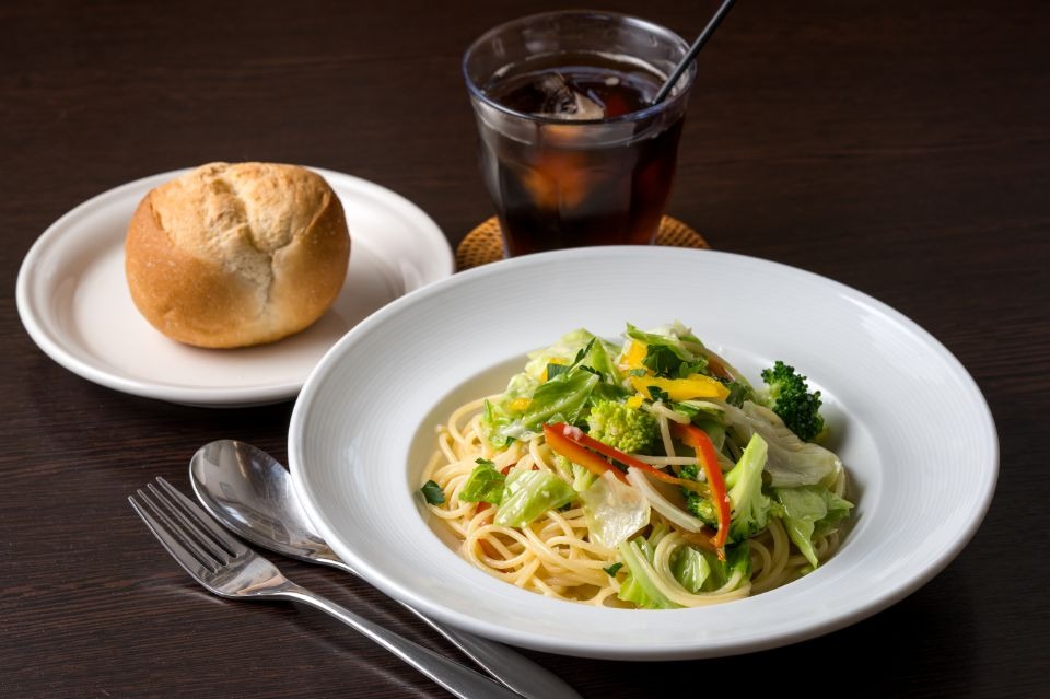 野菜たっぷりのペペロンチーノに、パンとアイスコーヒーが添えられた料理画像